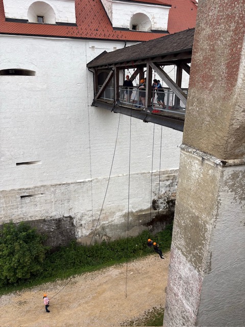 Personen stehen auf einer Brücke und seilen sich ab